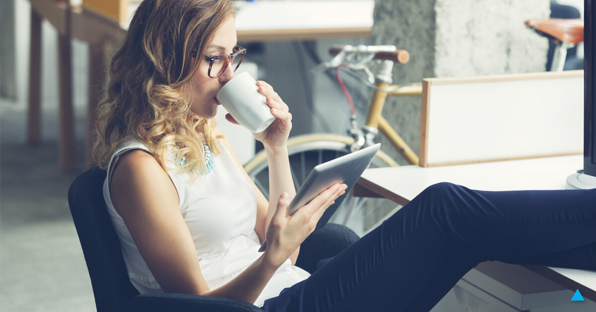 A woman reading on her tablet while drinking coffee. Learn more about content marketing.